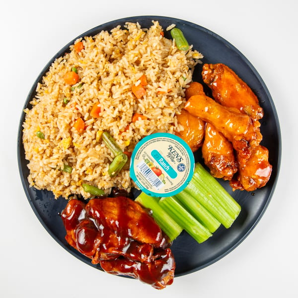 A plate of fried rice, barbecue wings, buffalo wings, celery sticks, and a ranch dressing cup.
