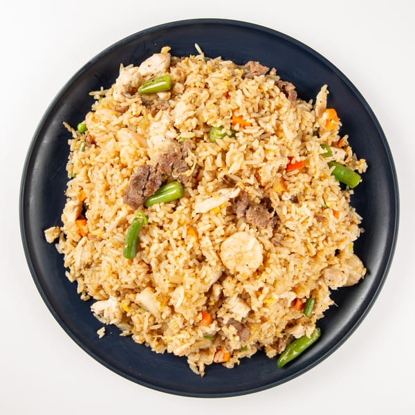 A dark plate filled with fried rice, chicken, beef, shrimp, green beans, and carrots.