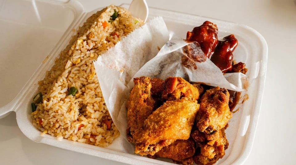 Takeout container with fried rice, crispy fried chicken wings, and saucy barbecue wings.